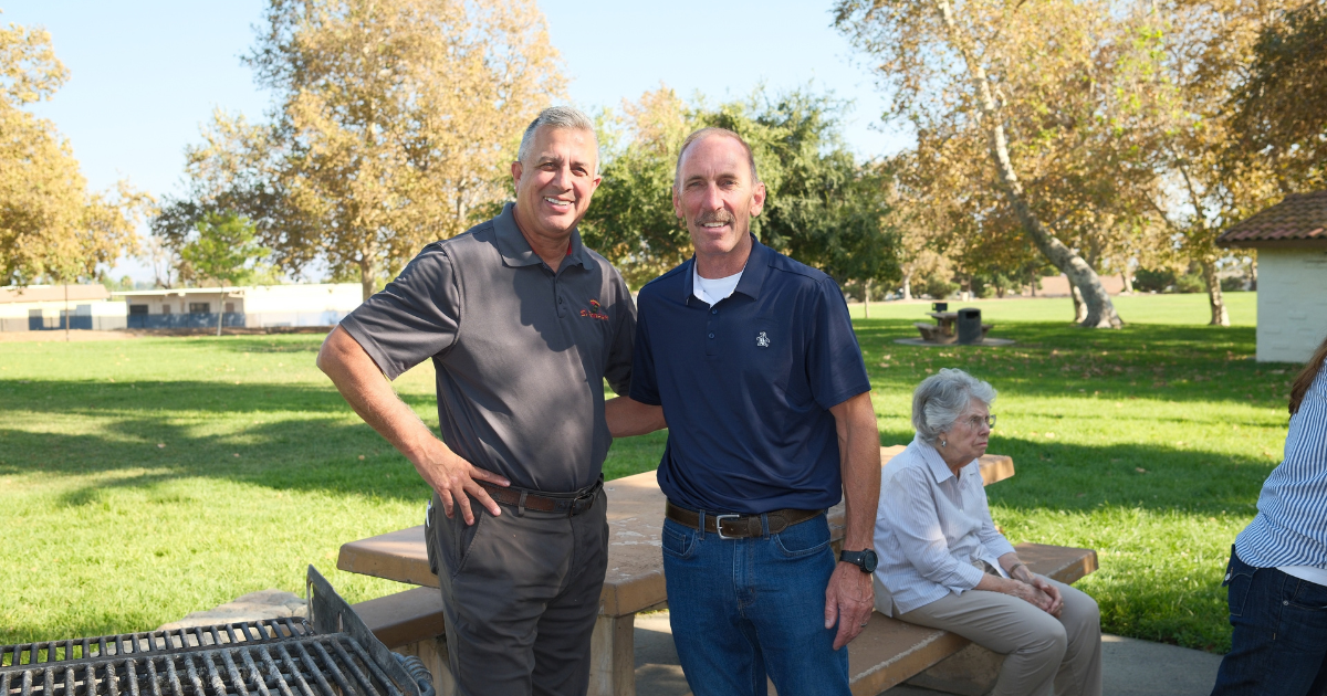 Art Andres standing with a community member at a park gathering