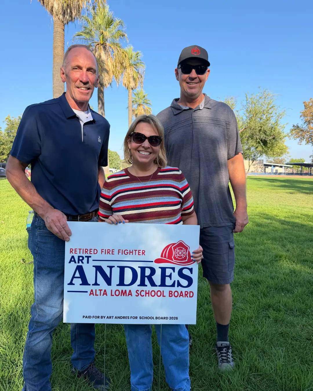 Art Andres and two supporters holding an Art Andres school board campaign sign